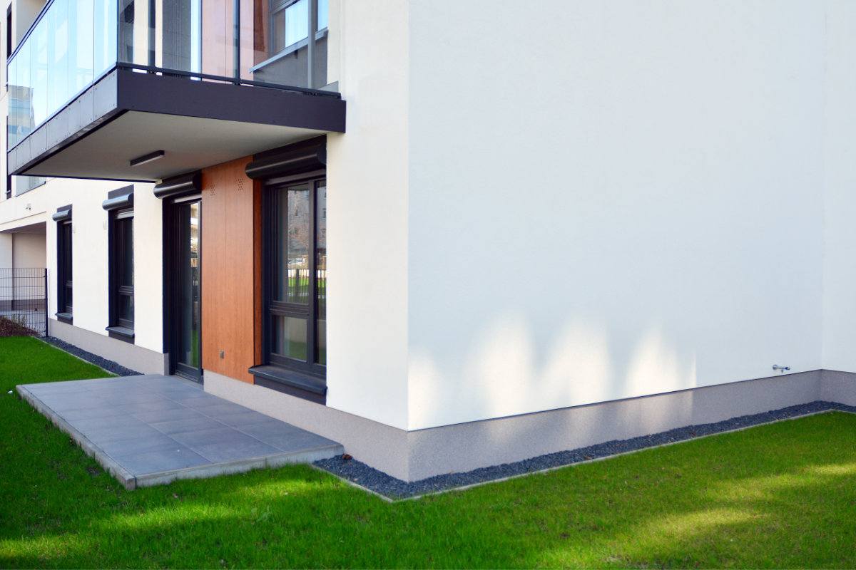Fassade eines weiß verputzten Hauses mit kleiner Terrasse und Balkon