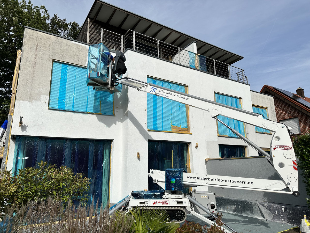 Anstricharbeiten mit Kran an weißer Hausfassade