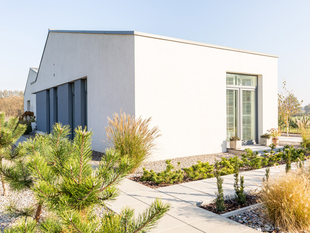 Weiß gestrichene Hausfassade mit Steinbeten und Blumen