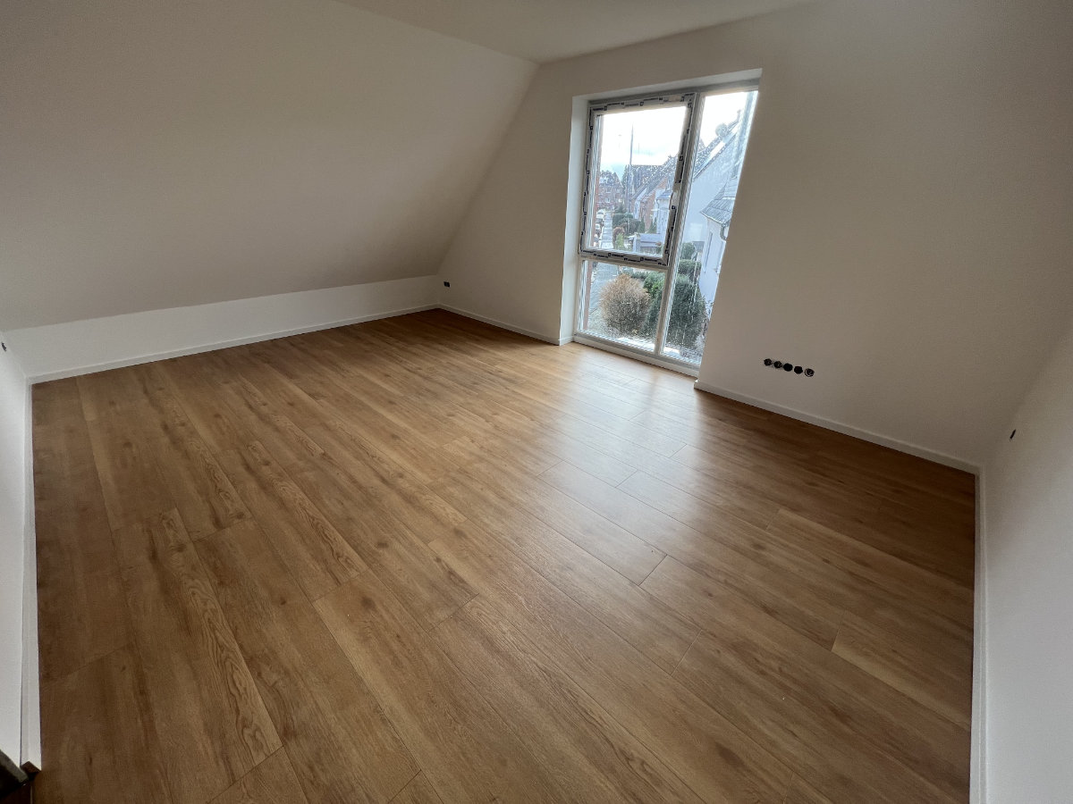 Heller Raum mit Holzboden und weiß gestrichenen Wänden