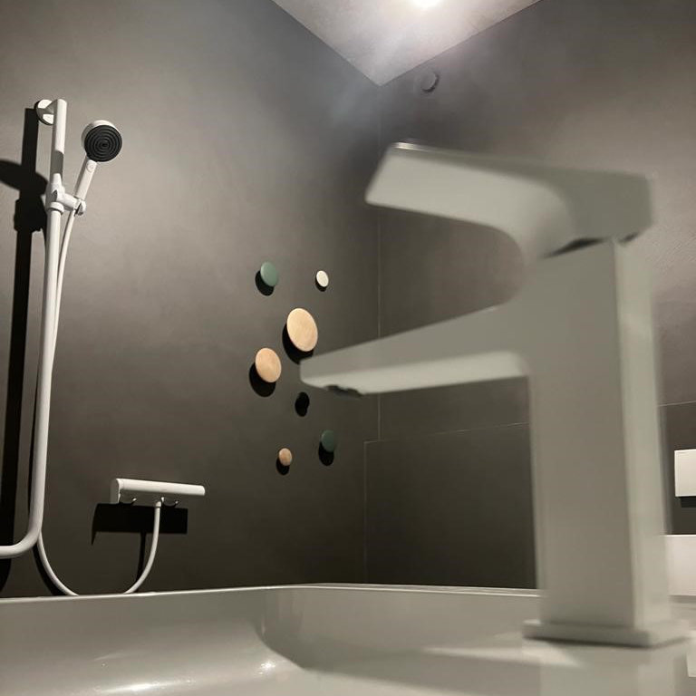 Graue Badezimmerwand und weiße Armaturen für Badewanne
