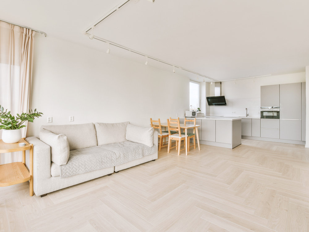 Heller Wohnbereich mit Küche und Sofa, Holzboden und weißen Wänden