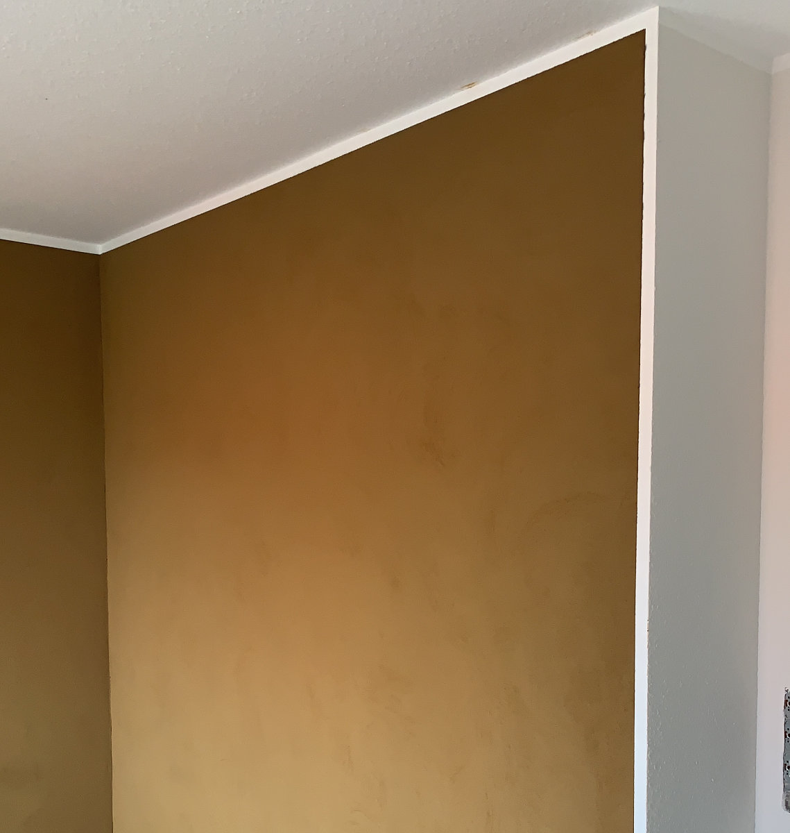 Braune Lehmputzwand mit weißer Decke