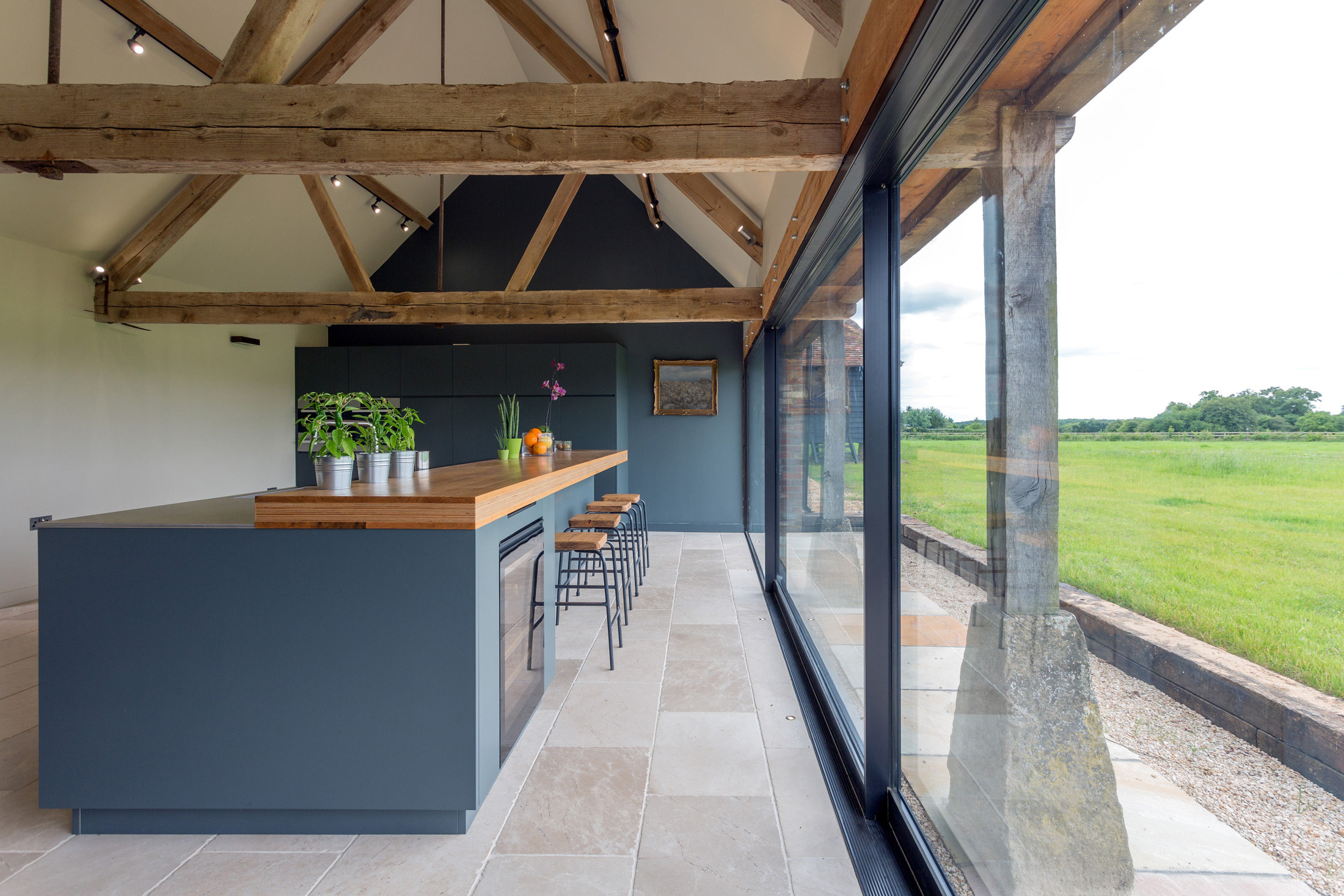 Renovierte Küche in Altbau mit großen Fenstern, alten Holzbalken und blau gestrichenen Wänden